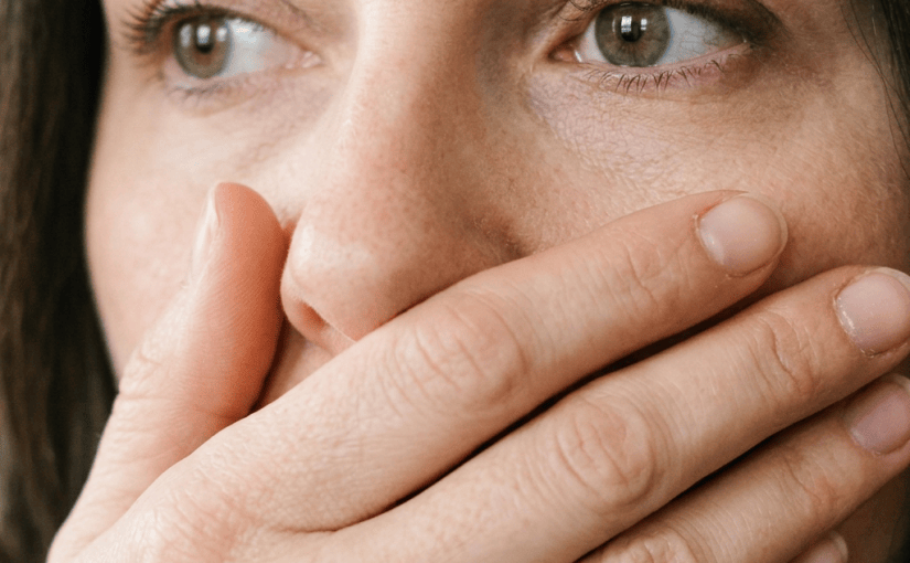 Woman in a dark sweater covering her mouth with her hand